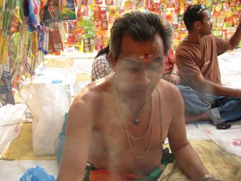 Hindu Priest surrounded with bags